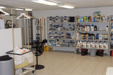 Organised cleaning supplies on shelves with a service cart