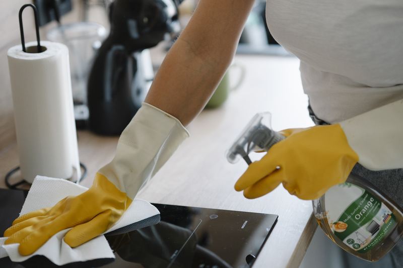 Person cleaning a kitchen surface with spray cleaner